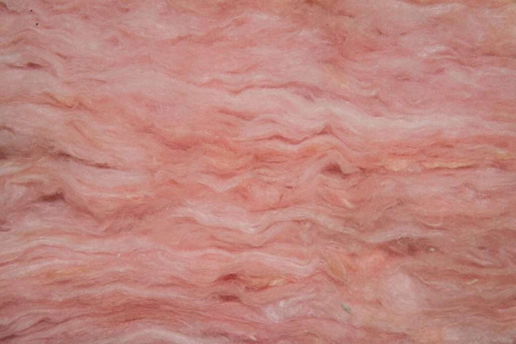 An extreme close up of one of the most popular types of home insulation: Fiberglass. It is cotton-like, dense, and pink.